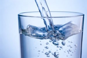 Close-up pouring water into glass on a blue background